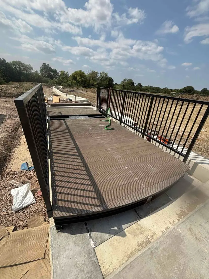 View along the bridge deck between black parapets, with construction works beyond.